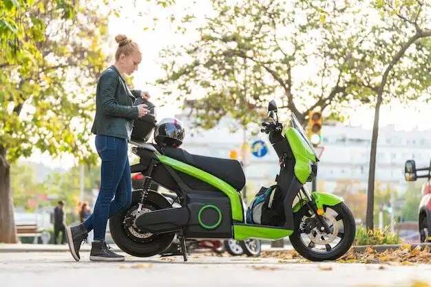 Une femme aux cheveux roux qui utilise le téléphone intelligent à côté de sa moto garée